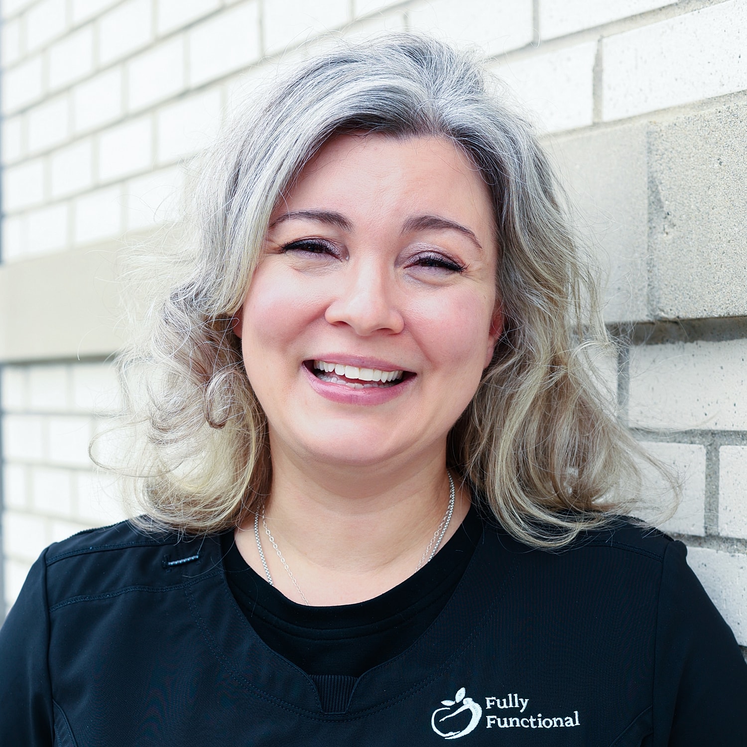 Smiling woman in healthcare uniform against wall.