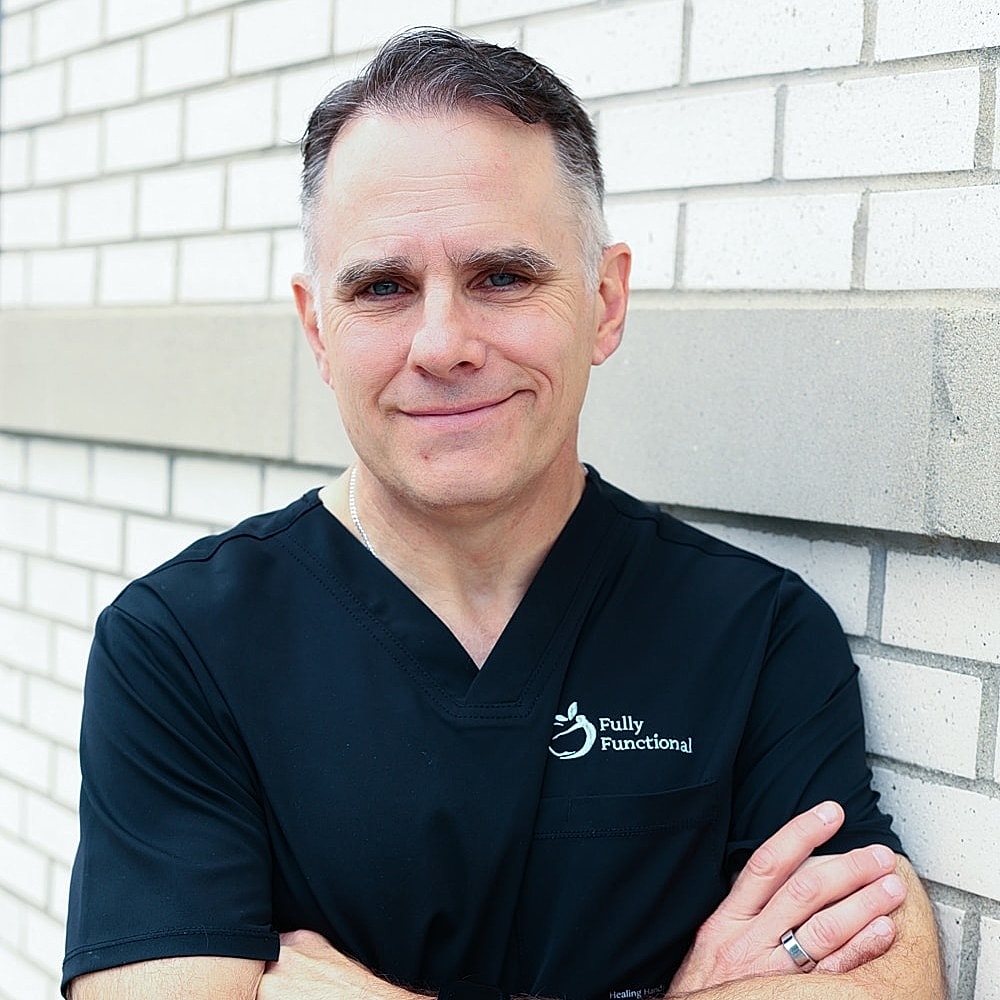 Male healthcare professional smiling against a wall.