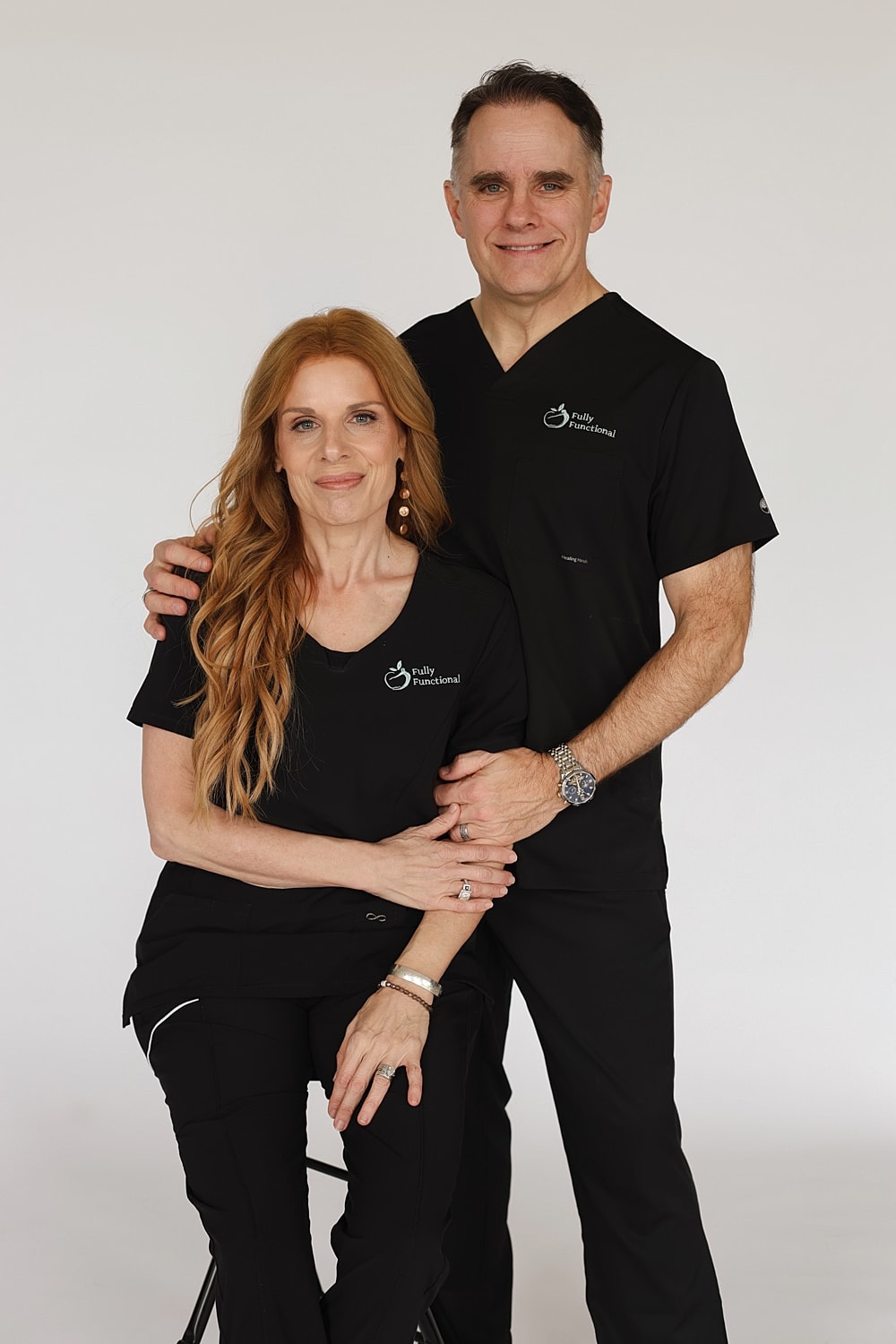Couple in black scrubs posing together.