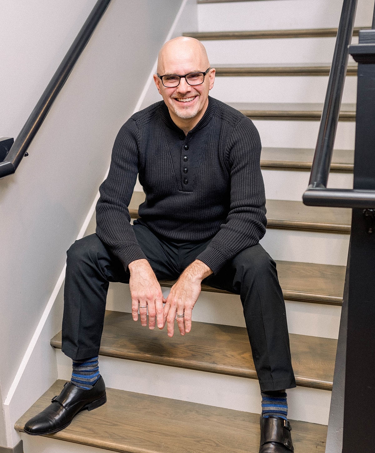 Man sitting on stairs, smiling confidently.