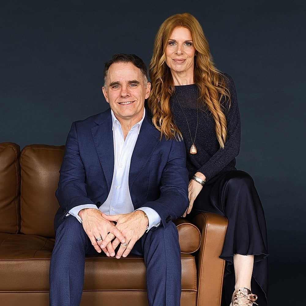 Couple seated on a couch, smiling at camera.