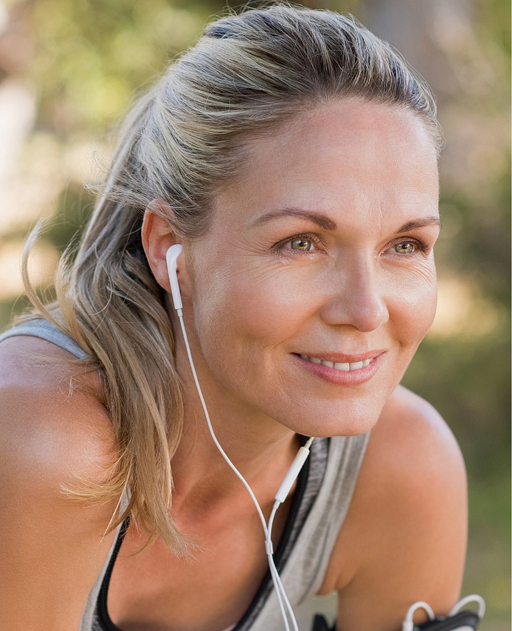 Smiling woman exercising with headphones outdoors.