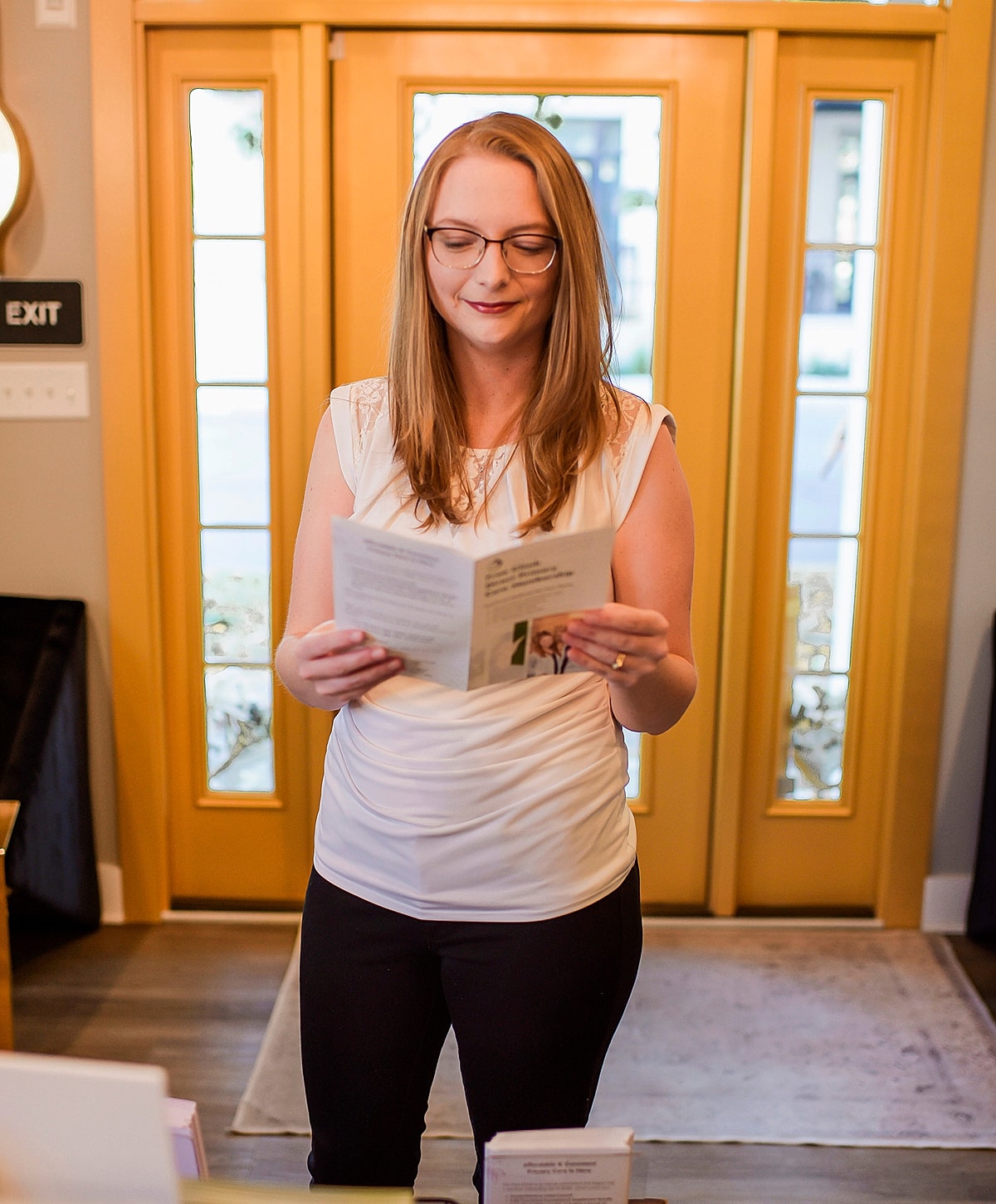Woman reading brochure near yellow doors.