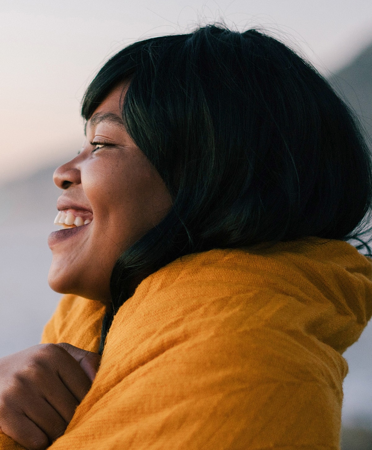 Smiling woman in yellow sweater outdoors.