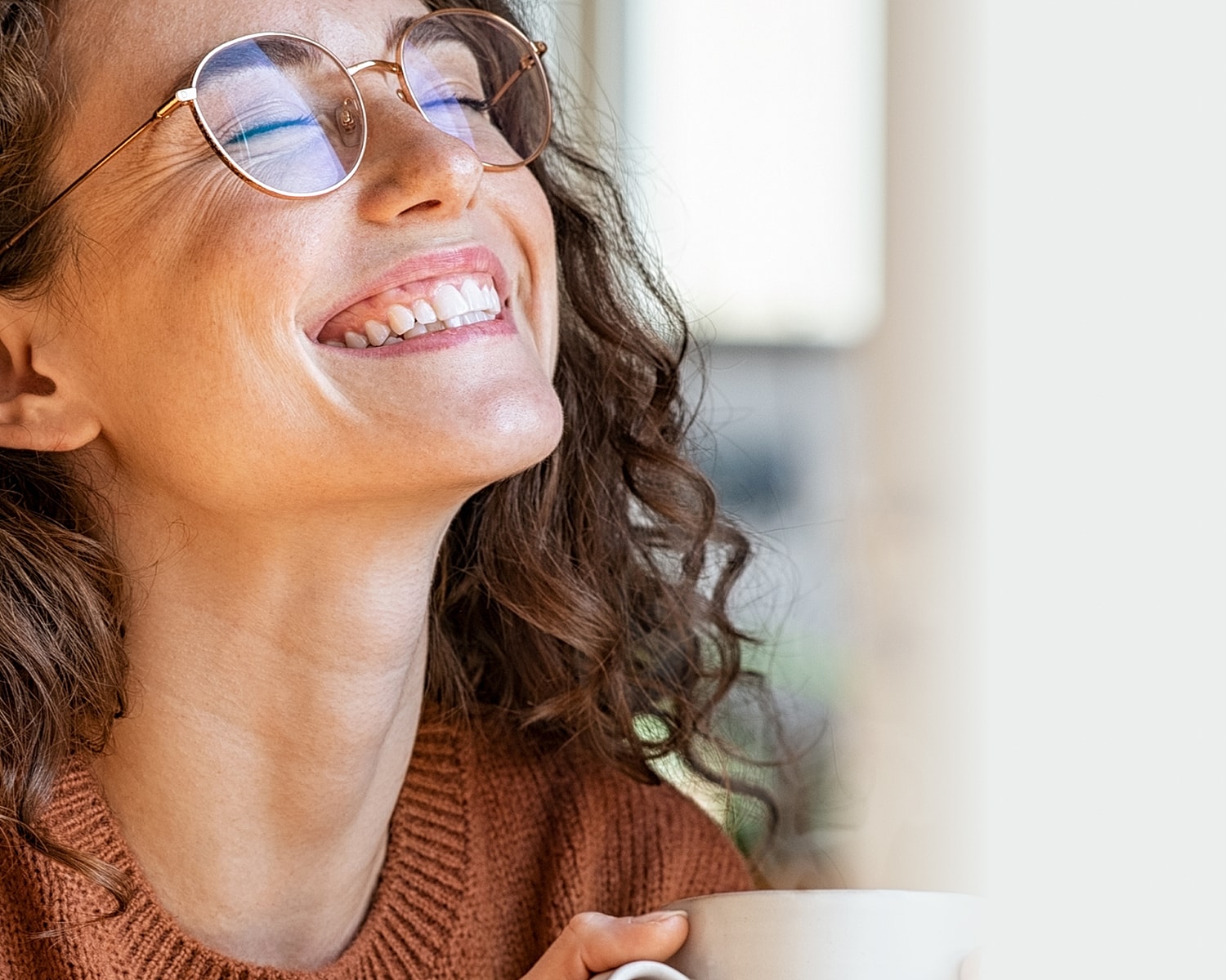 Smiling woman with glasses enjoying a drink.