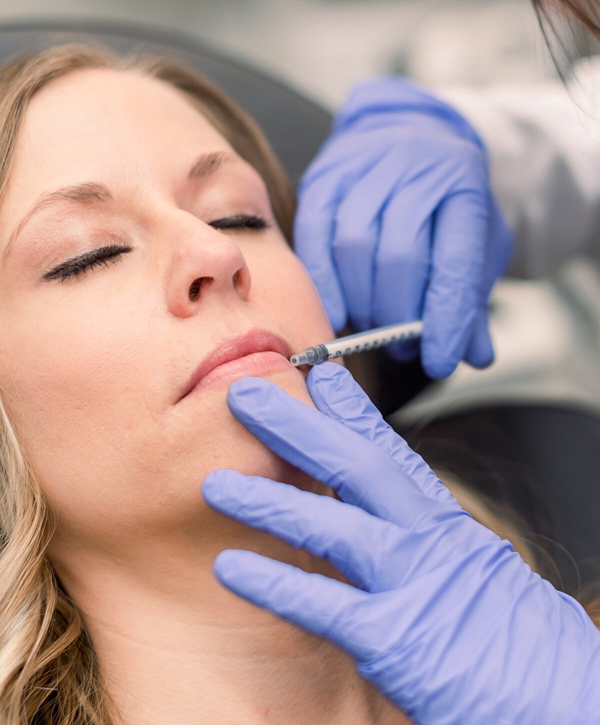 Woman receiving cosmetic lip injection procedure.