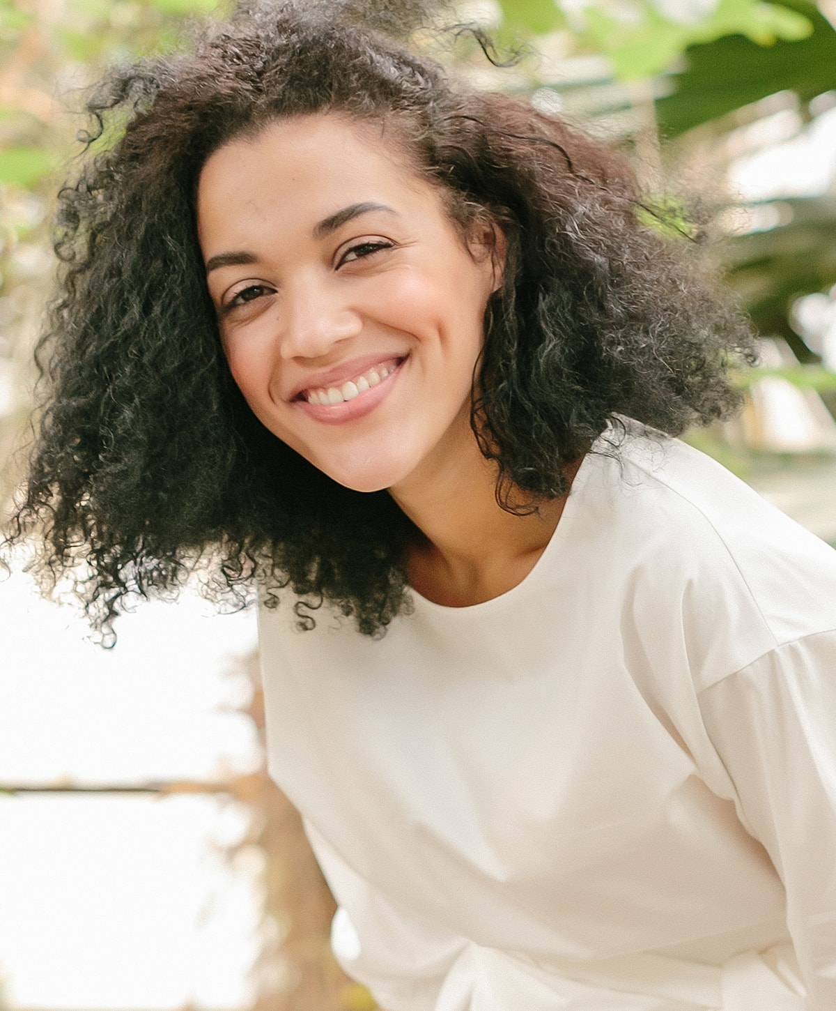 Smiling woman with curly hair outdoors.