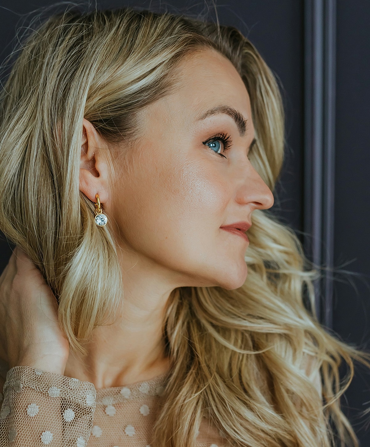 Woman with stylish earrings and wavy blonde hair.