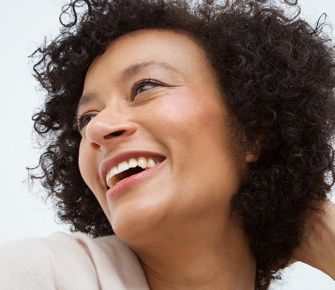 Smiling woman with curly hair, bright expression.