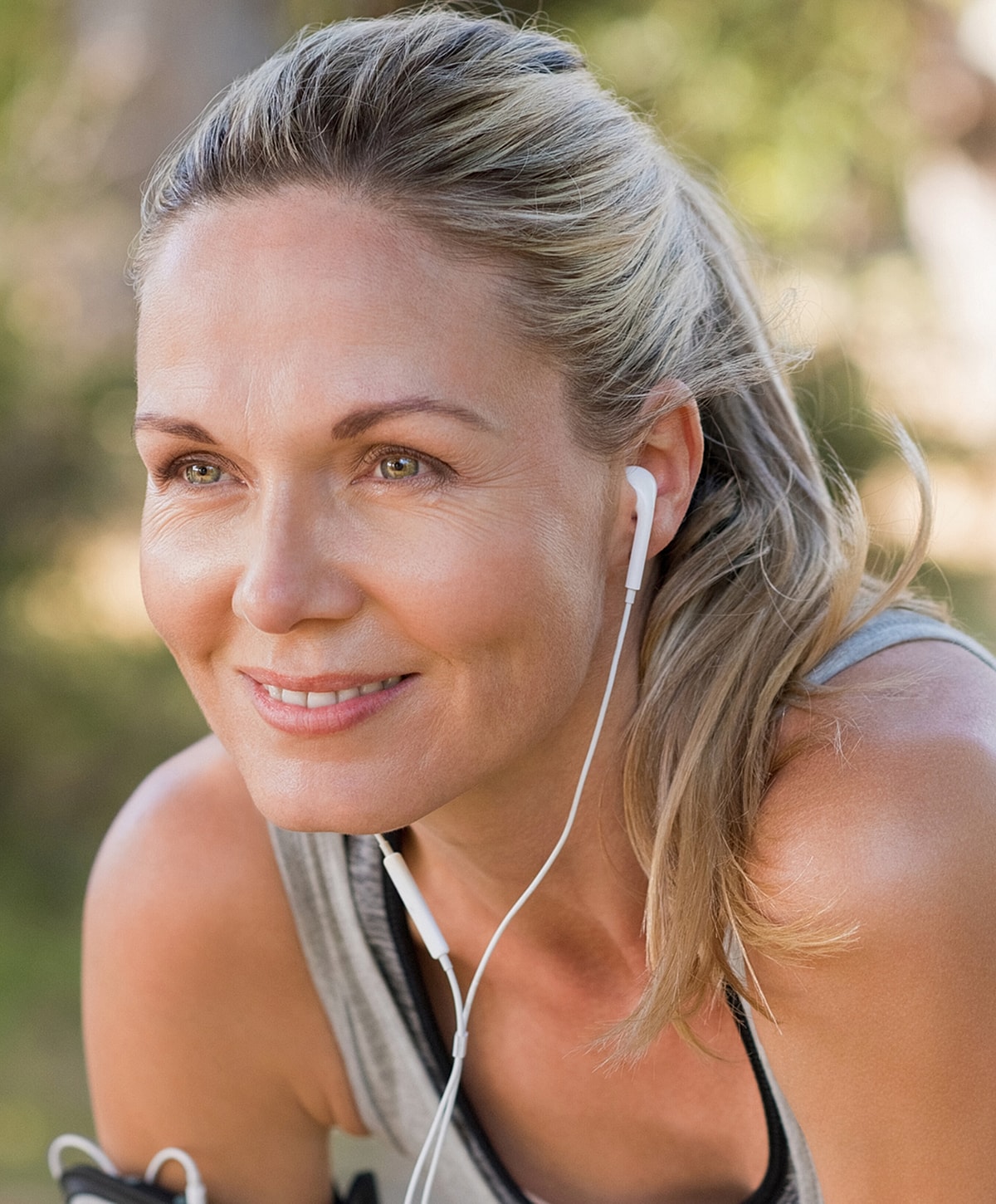 Smiling woman listening to music outdoors.