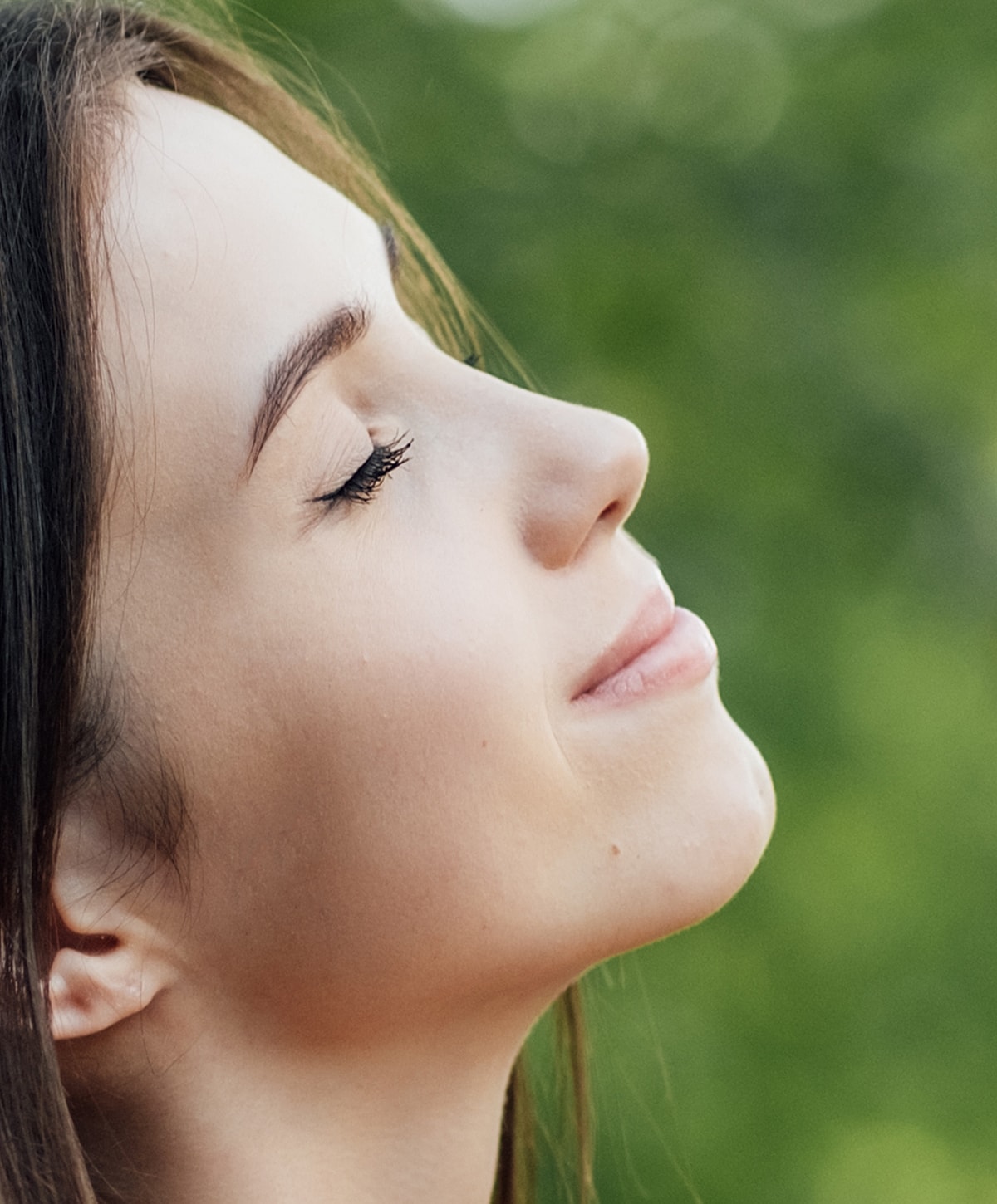 Profile of a young microneedling patient model outdoors, eyes closed.