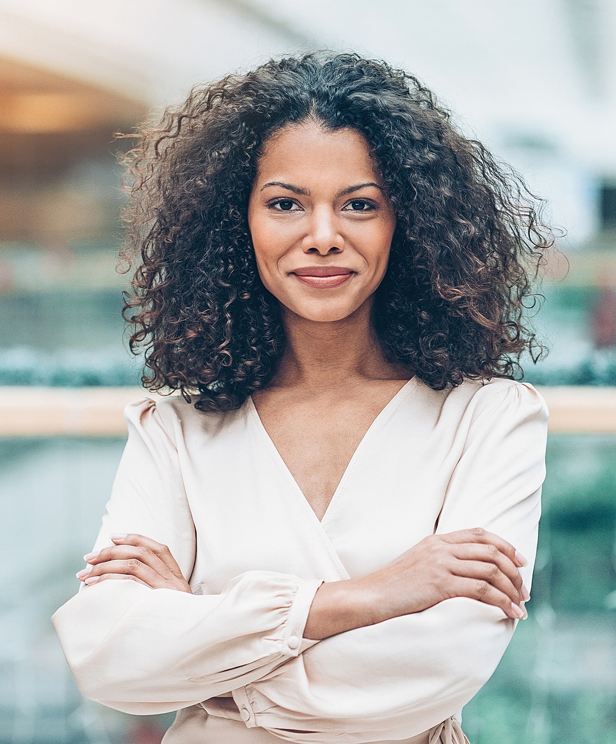 Smiling woman with curly hair, arms crossed.