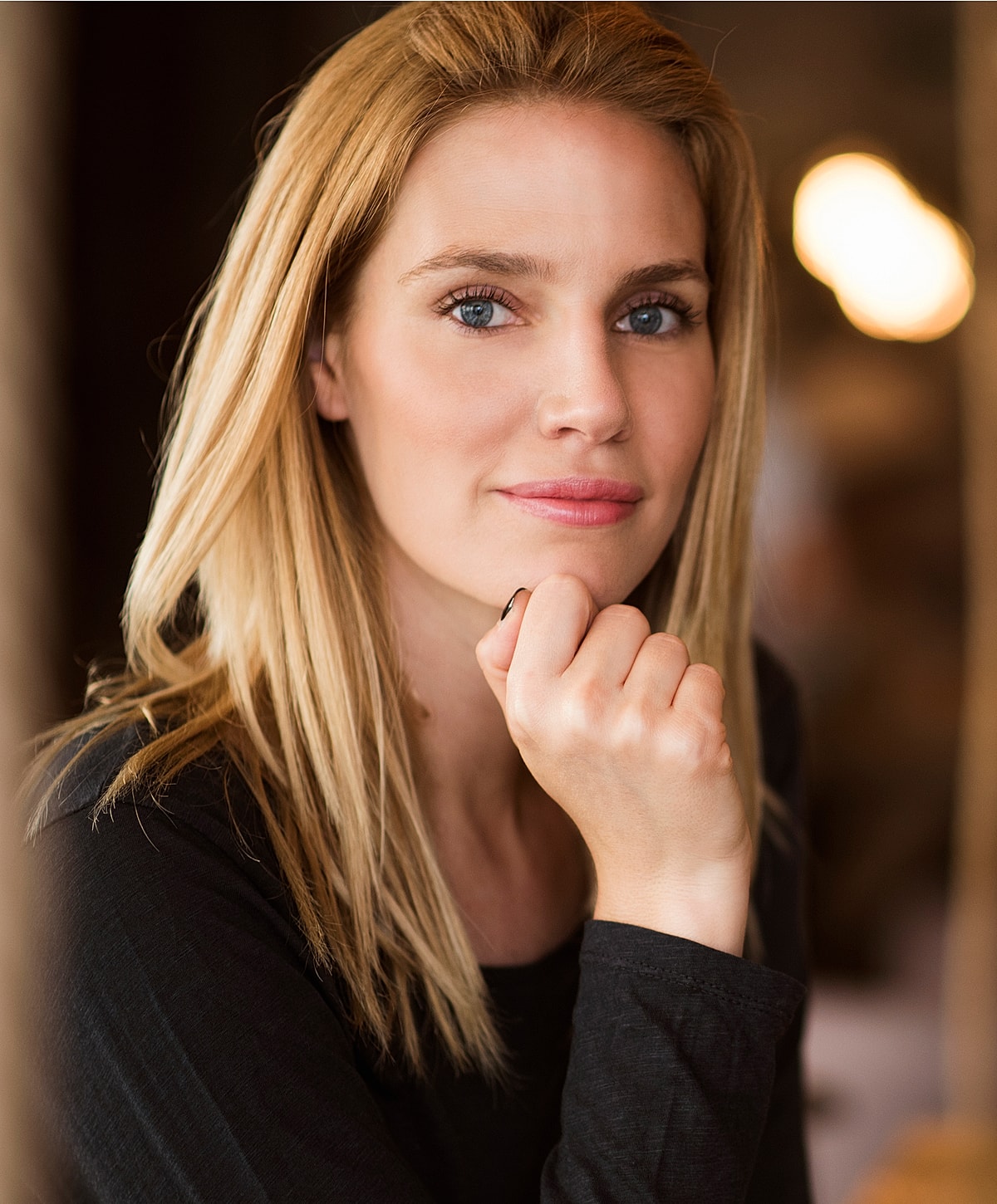 Woman resting chin on hand, thoughtful expression.