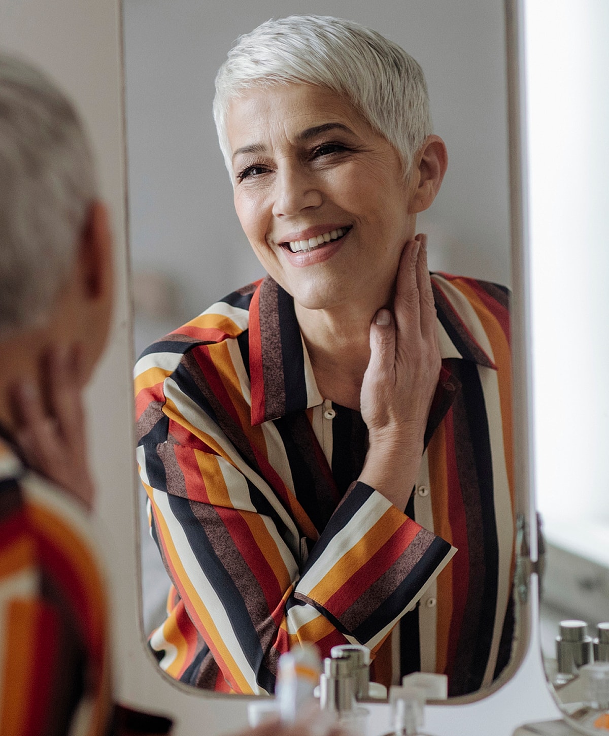 Smiling microneedling patient model with short hair in front of mirror.