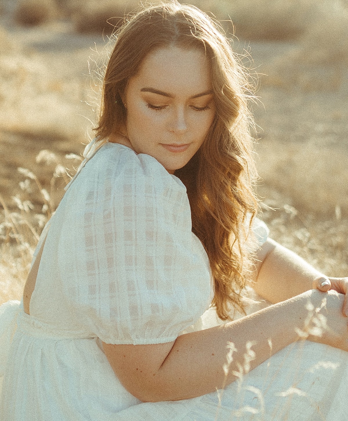 microneedling patient model in white dress sitting in sunlit field.
