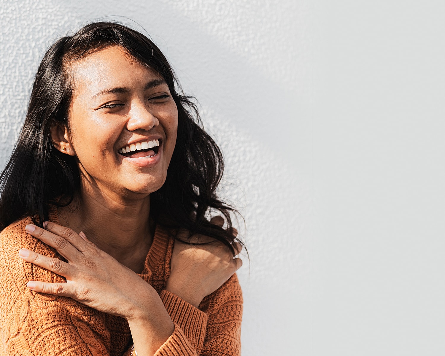 Smiling woman in cozy sweater laughing joyfully.