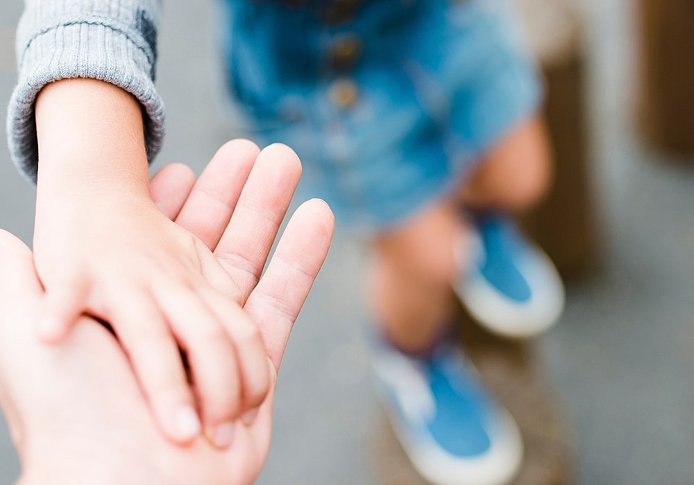 Hands of two people holding together gently.