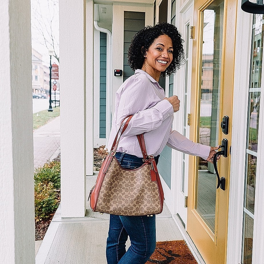 Smiling woman approaching a front door.
