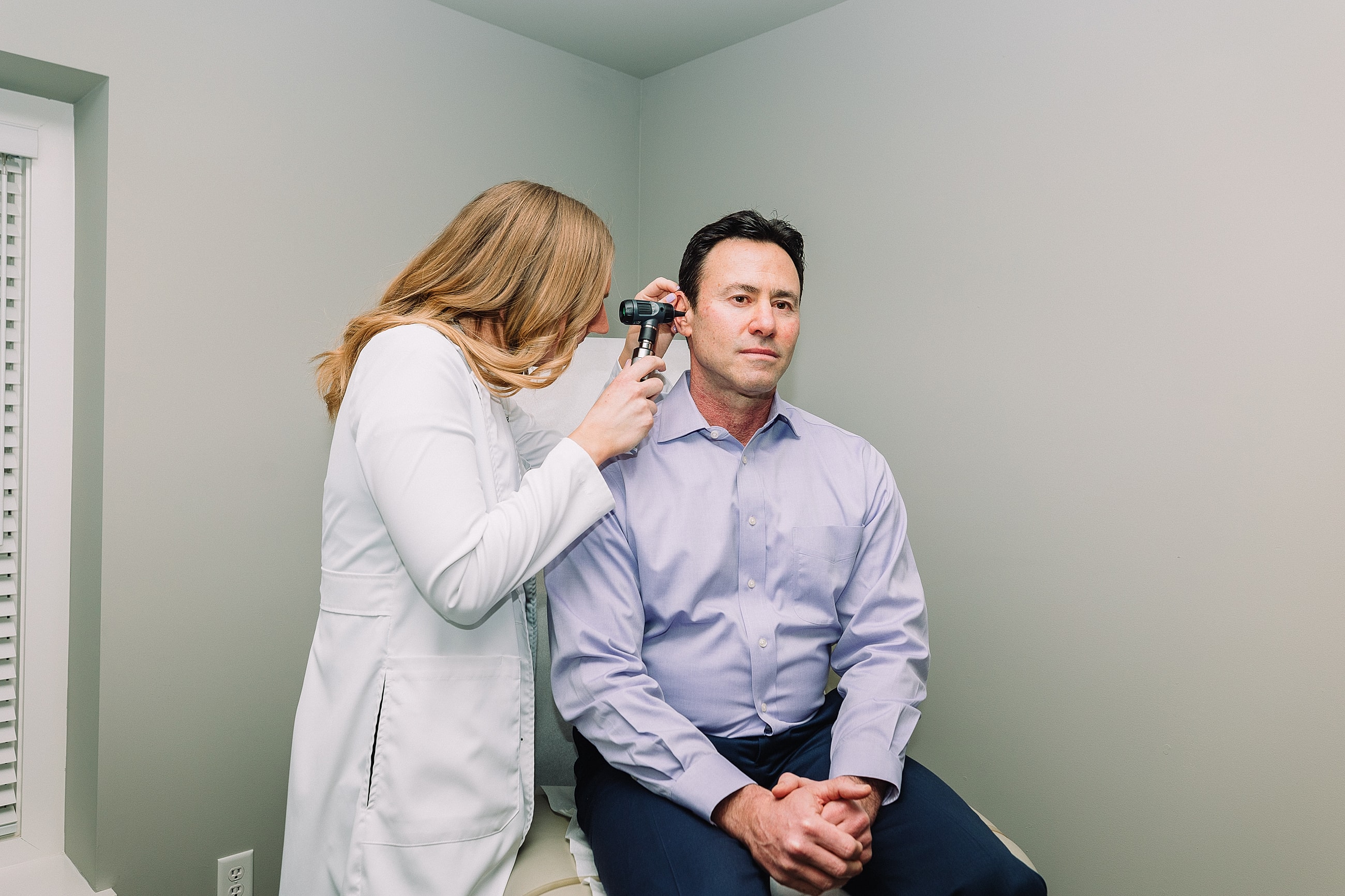 Doctor examining patient's ear in office setting.