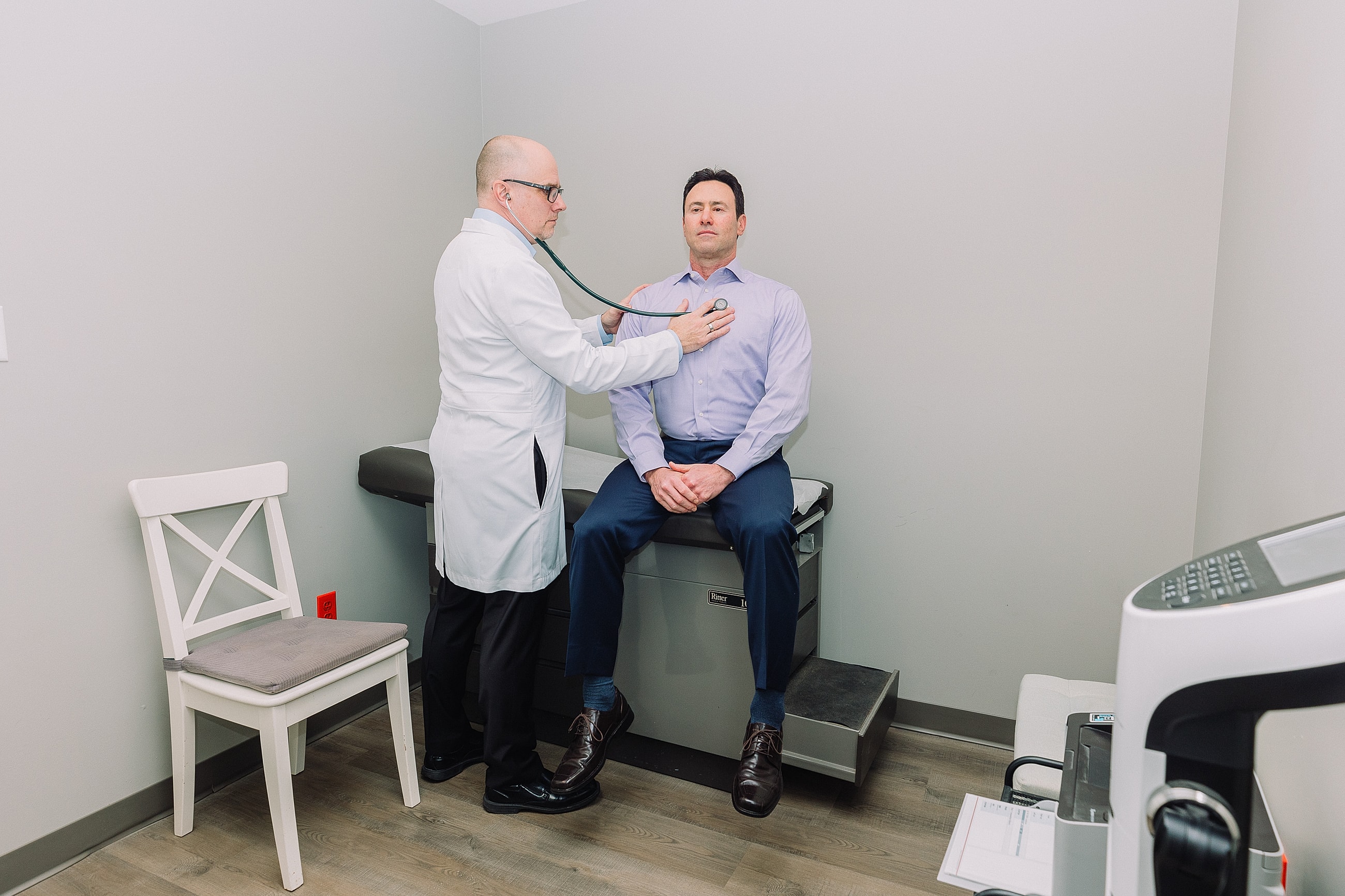 Doctor examining patient with stethoscope in office.