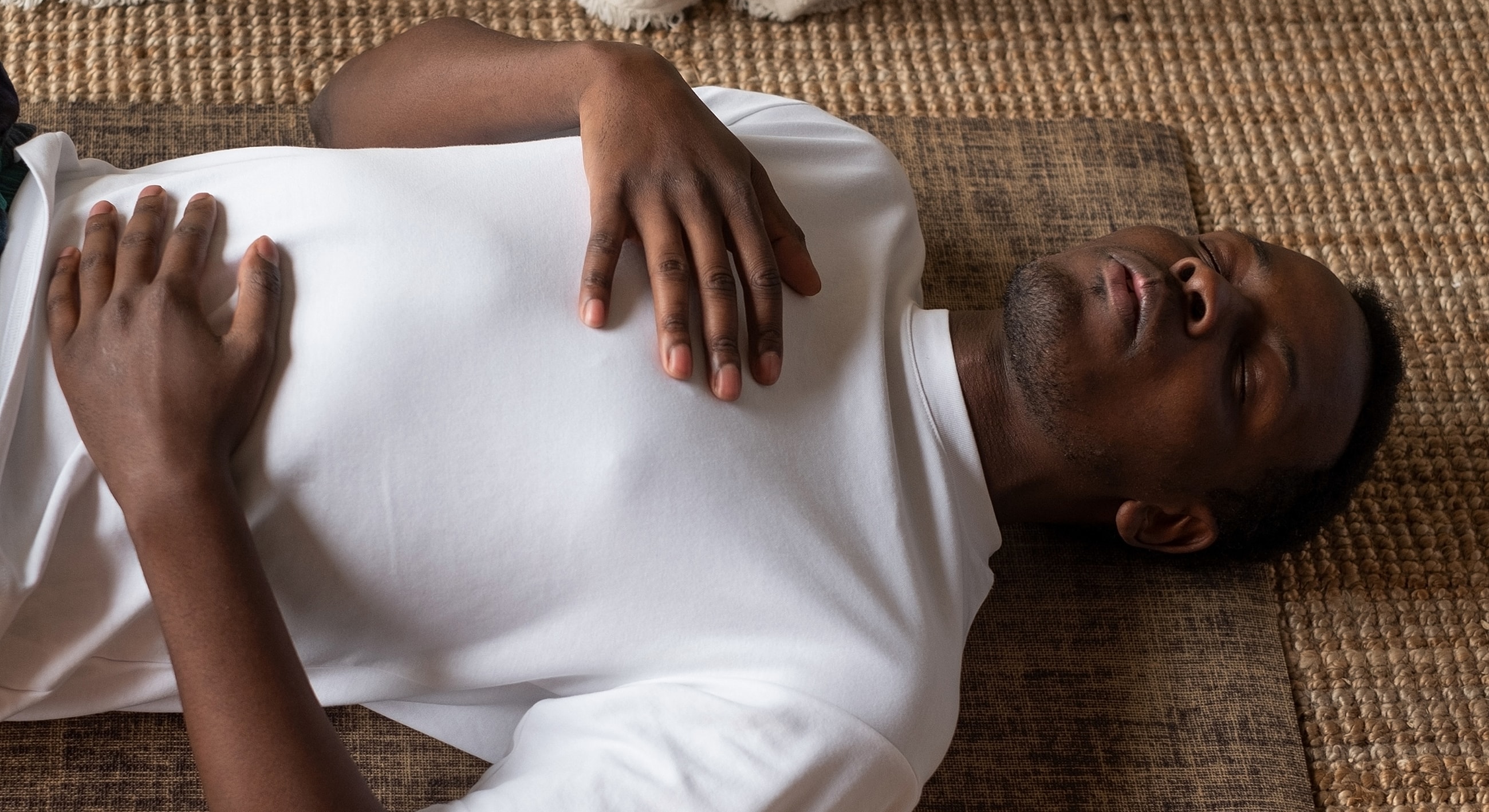 Person meditating on a mat indoors.