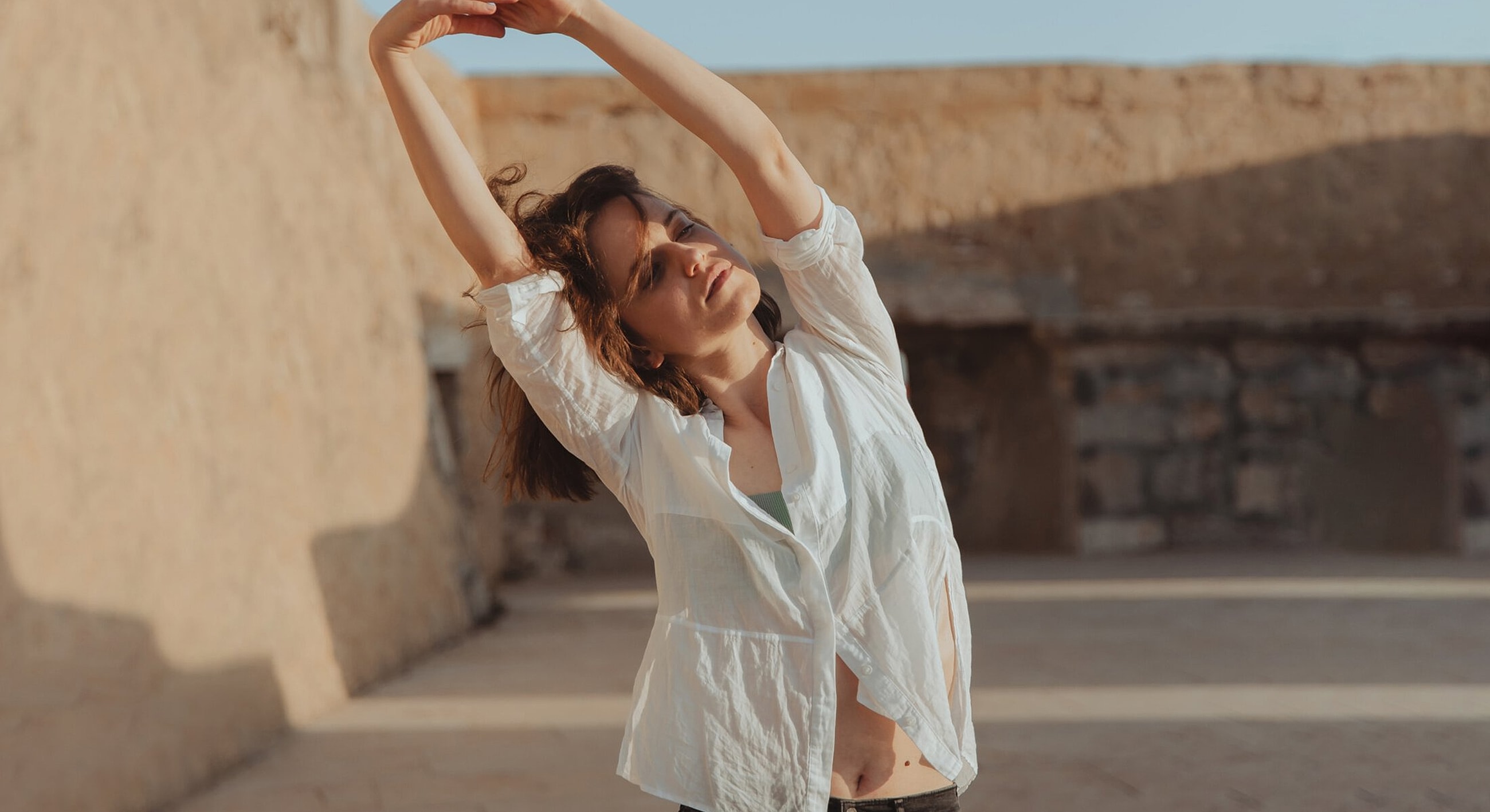 Woman stretching outdoors in casual attire.