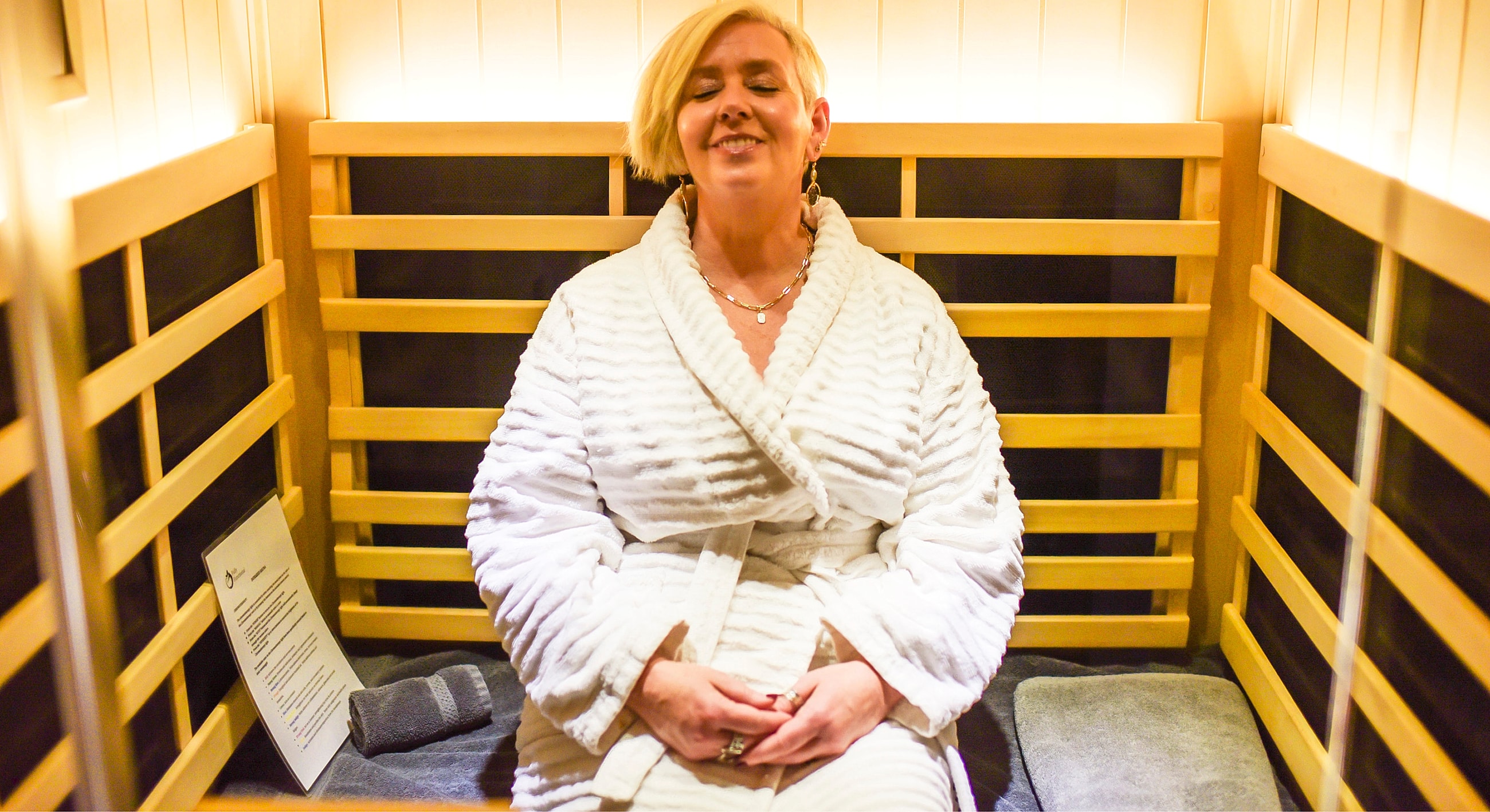 Relaxing woman in bathrobe inside sauna.