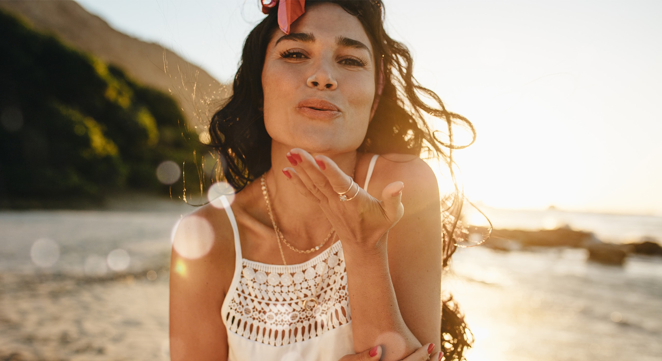 Woman blowing a kiss at sunset beach.