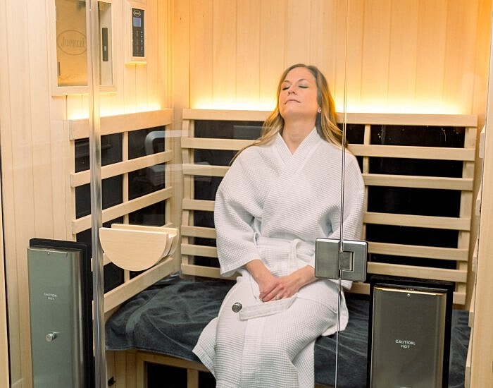 Woman relaxing in a sauna, wearing a robe.